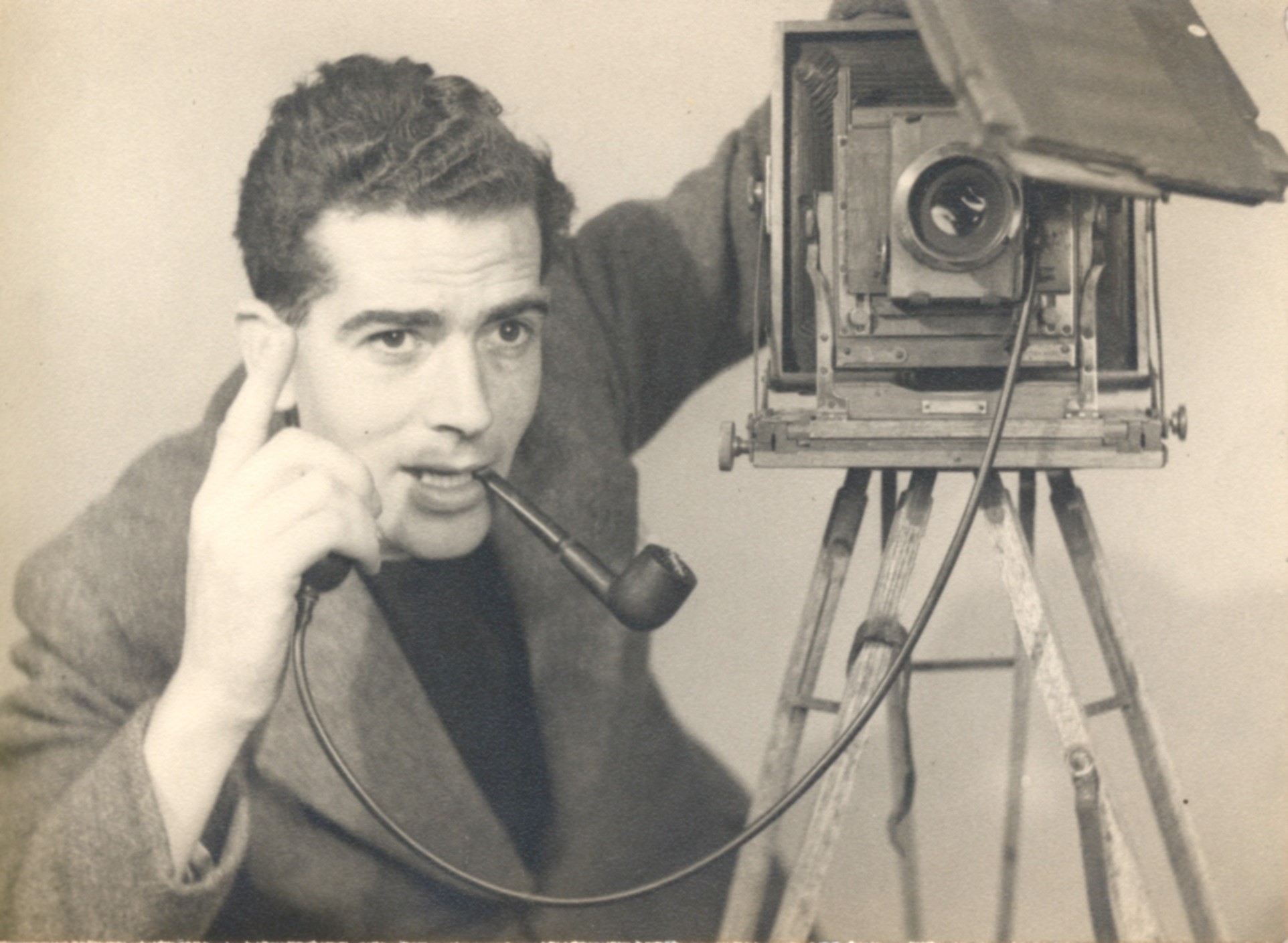 Image of Christine's father taken in the 1940s posing next to his camera with a pipe